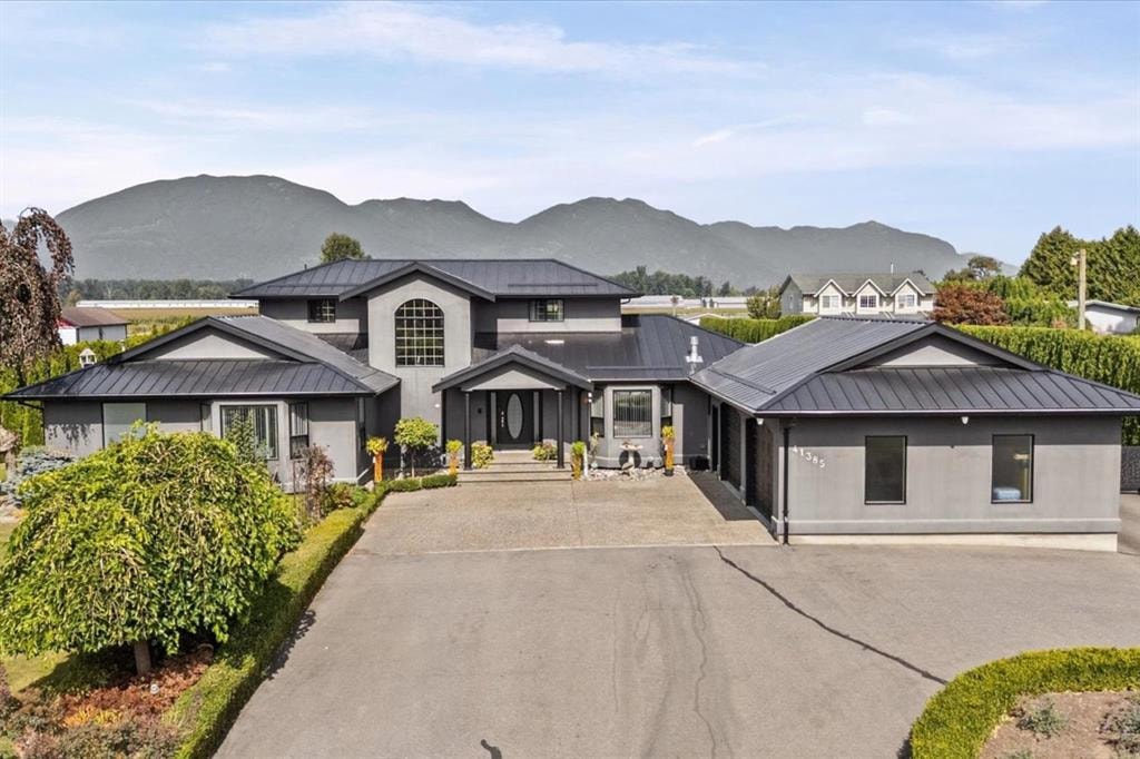 Modern gray luxury home with black metal roofs at 41385 South Sumas Road, Greendale, Chilliwack, with mountains behind